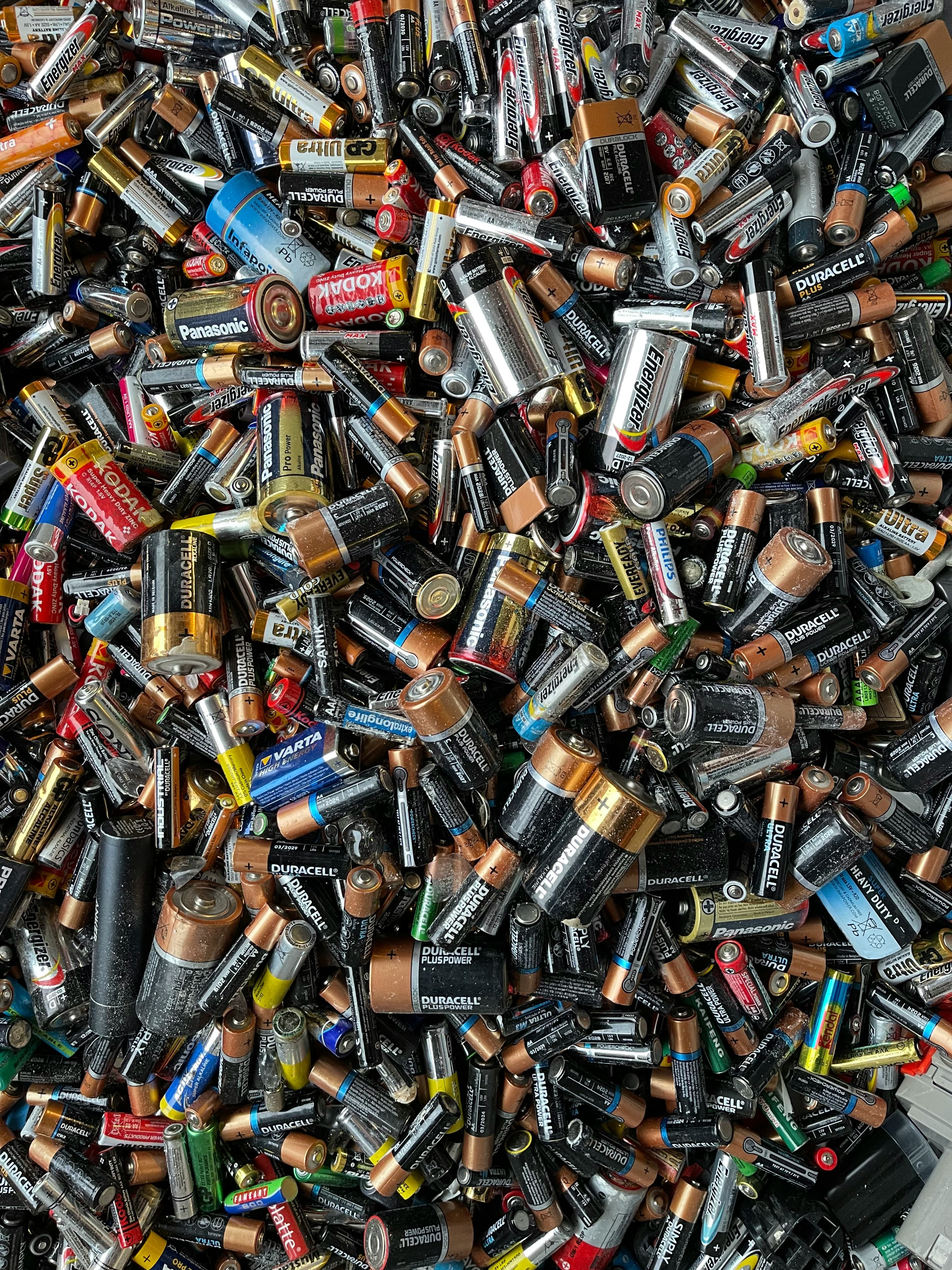 A heap of used household batteries of many brands and sizes