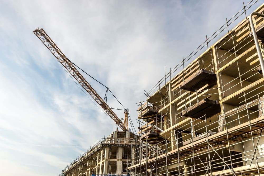 A tower crane beside a building wrapped in scaffolding